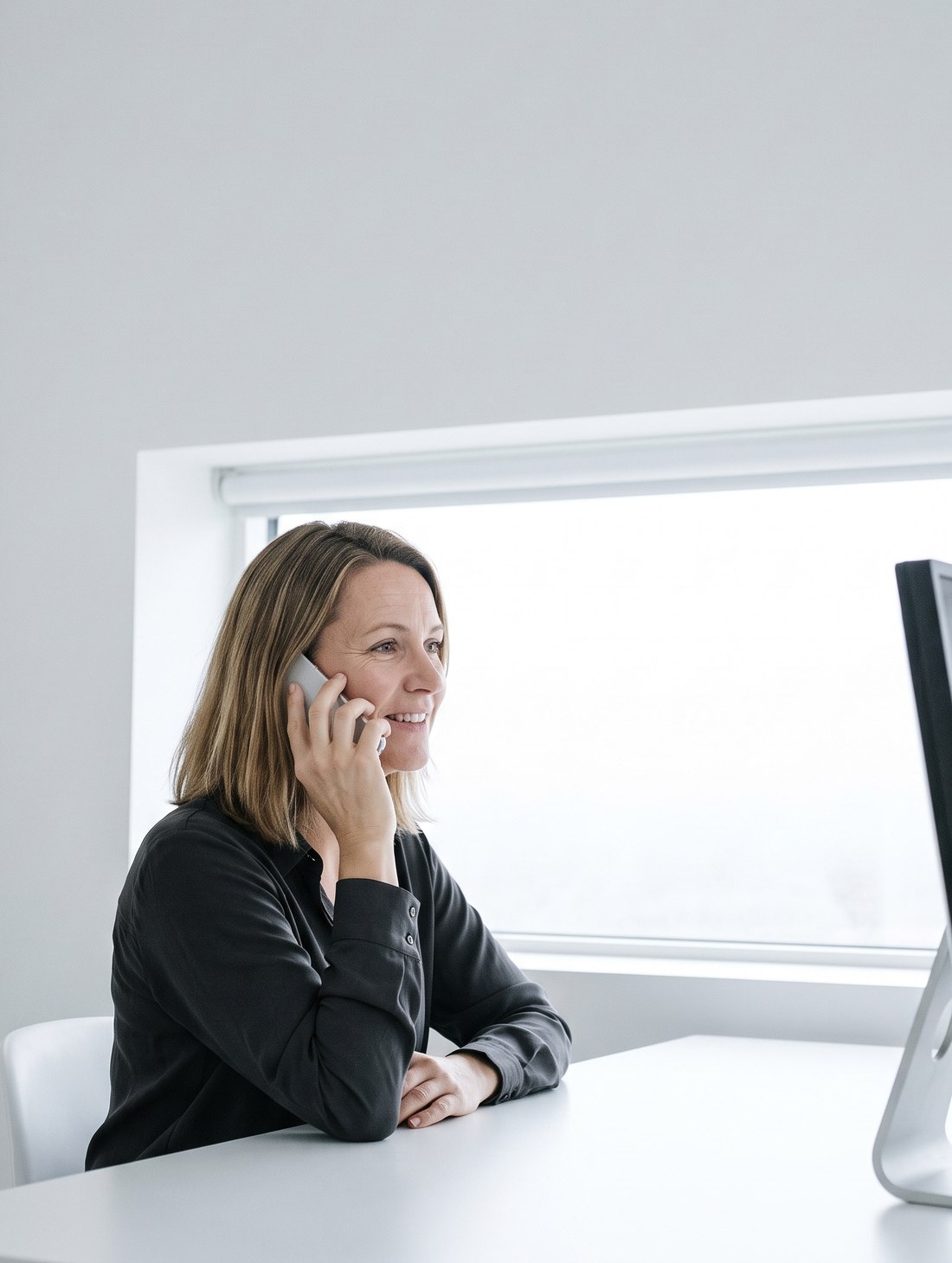 Mitarbeiterin im Vertrieb telefoniert am Schreibtisch